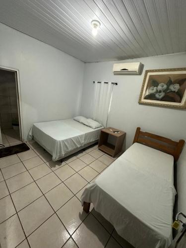 a bedroom with two beds and a tiled floor at Hotel São Cristóvão in Marabá