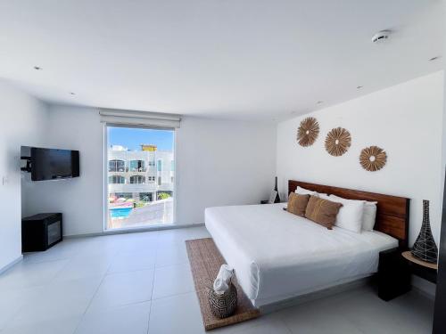 a white bedroom with a bed and a window at Cache Hotel Boutique - Adults Only in Playa del Carmen