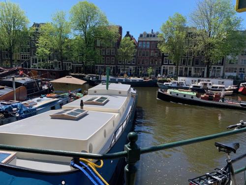 a boat is docked in a canal with other boats at Appartement op woonboot hartje centrum in Amsterdam