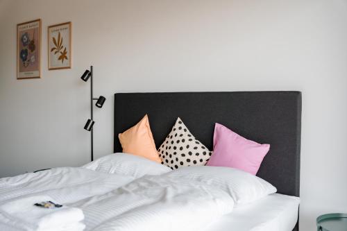 a bedroom with a white bed with colorful pillows at Skyrise Apartments - Stilvoll wohnen, entspannt genießen in Bad Wörishofen