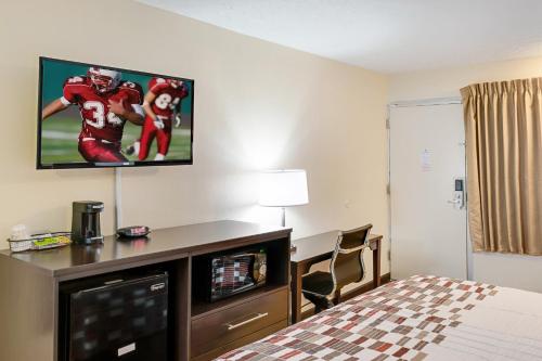 a hotel room with a bed and a tv on the wall at Red Roof Inn Indianapolis - Castleton in Indianapolis