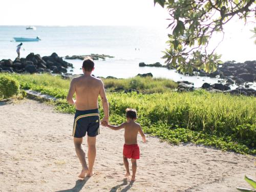 a man and a little boy standing on a beach at Flowers of Paradise in Mont Choisy