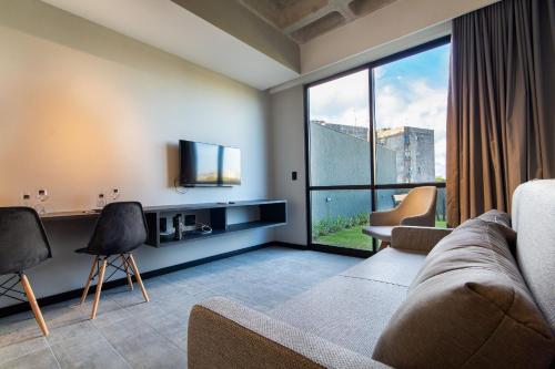 a living room with a couch and a tv at TOLIVE One Housi Recife by Carpediem in Recife