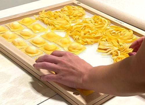 a person is preparing pasta on a tray at Rimini, 4 Camere con Giardino Privato e Parcheggio Gratuito, Relax a 10 Minuti dal Mare in Casalecchio