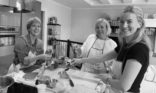 three women standing around a table in a kitchen at Rimini, 4 Camere con Giardino Privato e Parcheggio Gratuito, Relax a 10 Minuti dal Mare in Casalecchio