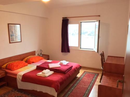 a bedroom with a bed with red sheets and a window at Main Bus Terminal Rooms in Dubrovnik