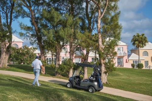 a man standing next to a golf cart at St George's Club in Saint George