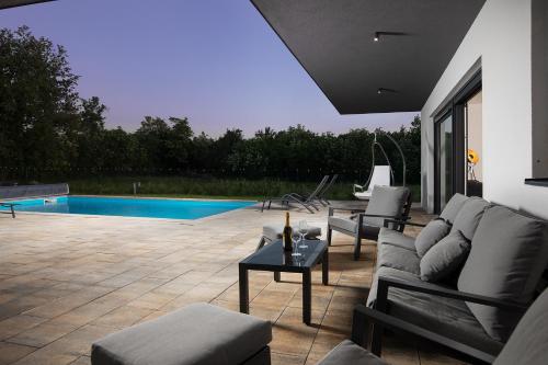 a patio with a couch and chairs and a pool at Vila Nora with heated pool in Marčana