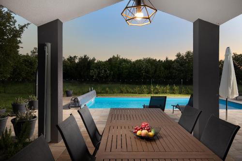 a wooden table with a bowl of fruit on a patio at Vila Nora with heated pool in Marčana