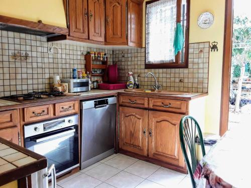 une cuisine avec des armoires en bois et des appareils en acier inoxydable dans l'établissement Eden appartement T2 dans aile de villa, à La Londe-les-Maures