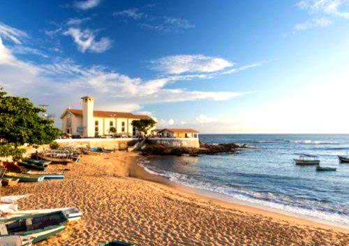 a beach with a house and boats on the water at Flat Vista Mar com Piscina e Wi-Fi Rápido Rio Vermelho in Salvador