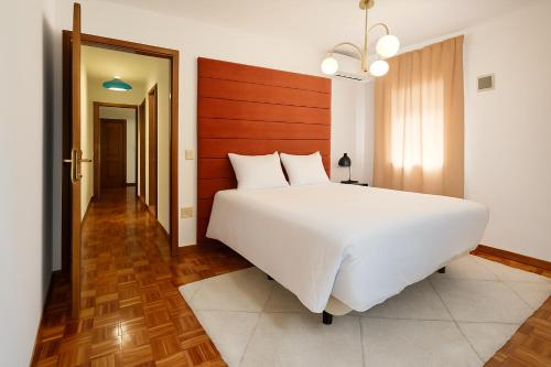a bedroom with a large white bed with a wooden headboard at Peach House T2 Fireplace in Ferro