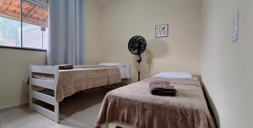 a room with two beds and a fan and a window at Casa próxima ao Parque das Águas in São Lourenço