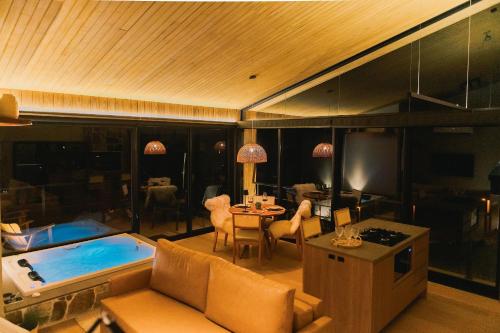 a living room with a swimming pool and a table at Elegante bangalô de campo 5 - Taquaras Huts in Rancho Queimado