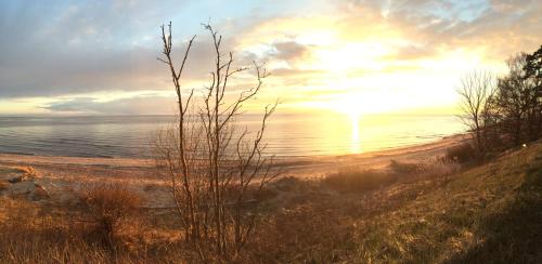 a sunset over a beach with the ocean in the background at Villa Gāles Hotel in Saulkrasti