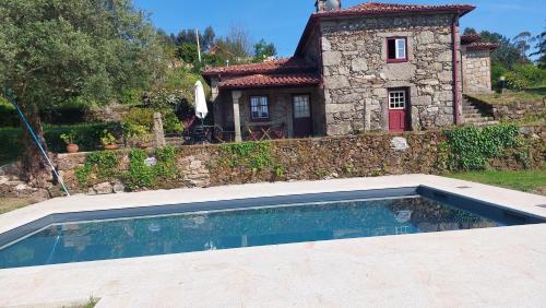 a house with a swimming pool in front of a house at Casa da Ramada, Turismo Espaço rural. in Ponte de Lima