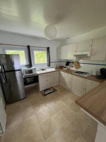 une cuisine avec des armoires blanches et un réfrigérateur en acier inoxydable dans l'établissement Petite maison 2 pas du centre ville, à Lannion