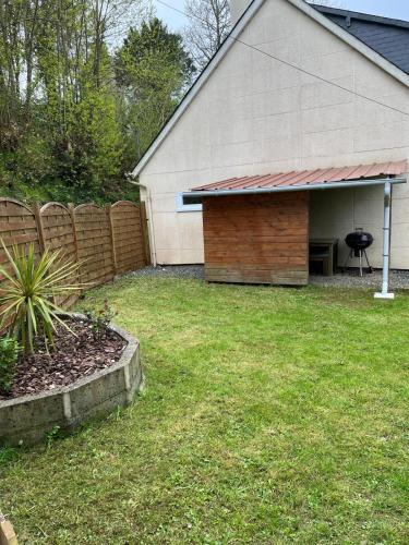 une cour arrière avec un bâtiment avec une clôture et un gril dans l'établissement Petite maison 2 pas du centre ville, à Lannion