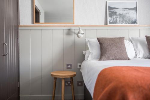 a bedroom with a bed and a stool next to it at Bosville Hotel in Portree
