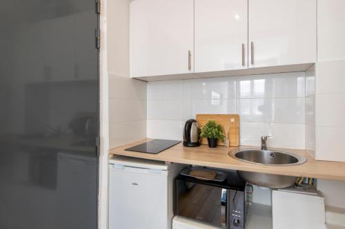 une cuisine avec des armoires blanches et un évier dans l'établissement Parisian Getaway for two in iconic Montmartre neighborhood, à Paris