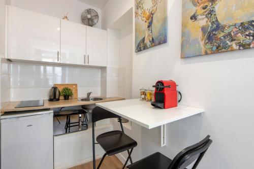 une petite cuisine avec un comptoir blanc et un appareil rouge dans l'établissement Parisian Getaway for two in iconic Montmartre neighborhood, à Paris