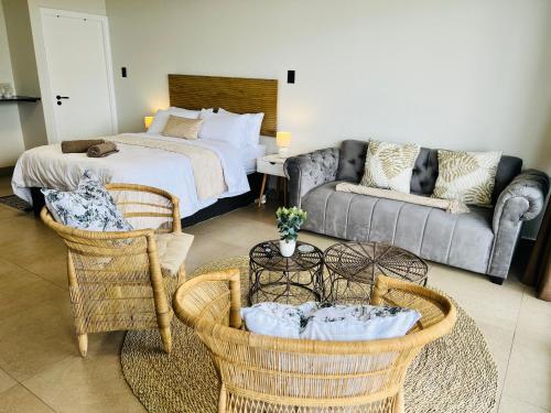 1 dormitorio con 1 cama, 2 sillas y sofá en Camarque - Umdloti's Ocean Escape, en Umdloti