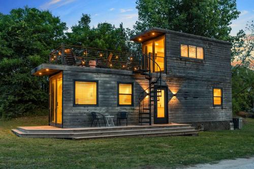 a small house with a balcony on the grass at Stunning 2-Story Container Home with Rooftop Terrace in Bellmead