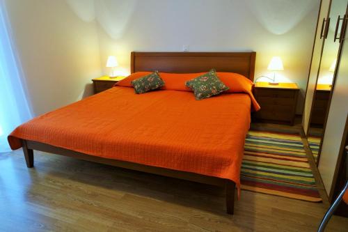 ein Schlafzimmer mit einem orangenen Bett mit zwei Kissen in der Unterkunft Apartments Harmonija in Baška Voda