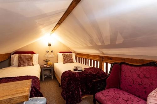 a attic room with two beds and a chair at Scenery Hill Hideaways The Coach House Charming Retreat with Jacuzzi and BBQ Hut Near the Lake District in Workington
