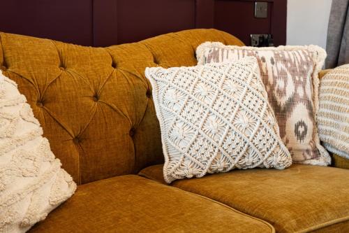 a brown couch with pillows on top of it at Scenery Hill Hideaways The Coach House Charming Retreat with Jacuzzi and BBQ Hut Near the Lake District in Workington