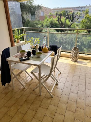 a white table and chairs in a room with a balcony at Apt "Laura" Terrasse - Parking - Plage - 5pers in Juan-les-Pins