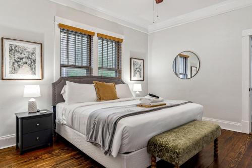 a white bedroom with a large bed and a stool at Fifth Street Retreat by StayLage in St. Charles