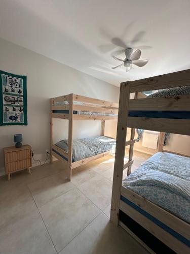 une chambre avec deux lits superposés et un ventilateur de plafond dans l'établissement Maison familiale et conviviale proche océan avec terrain de pétanque, au Château-dʼOléron