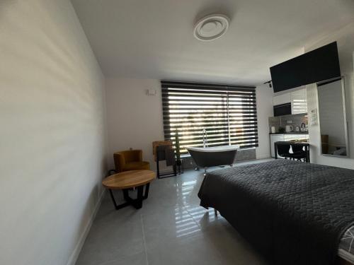 a bedroom with a bed and a table and a kitchen at New Apart Smart- OAZA RELAKSU-Rynek Central Kielce - Parking -fak VAT- rok budowy 2025 in Kielce