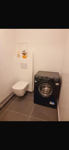 une salle de bain avec machine à laver et toilettes dans l'établissement Appartement neuf et moderne à Puteaux, à Puteaux