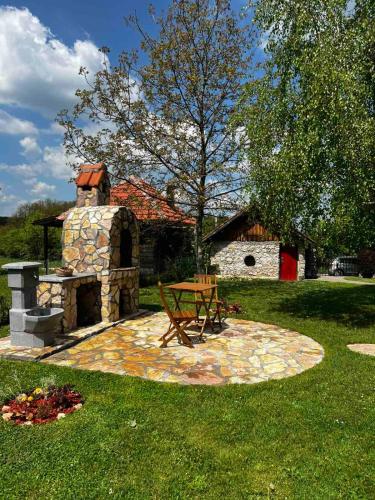 a picnic table and a stone fireplace in a yard at Brvnara Nenadić in Užice