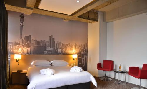 um quarto de hotel com uma cama e cadeiras vermelhas em Reef Hotel em Joanesburgo