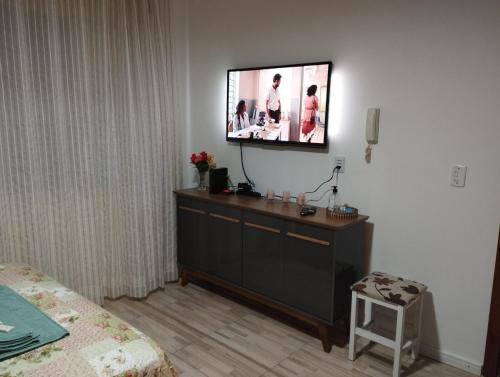 a tv on a wall with a dresser in a bedroom at Consulado Americano Studio 40 mts do Consulado do Estados Unidos in Porto Alegre
