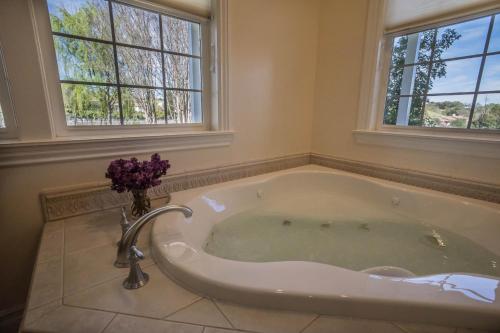 a bath tub in a bathroom with two windows at ONX WINES - Clark House & Apartment in Templeton