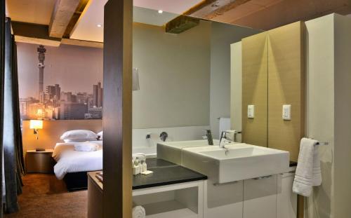 baño con lavabo y cama en Reef Hotel en Johannesburgo