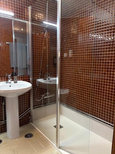 een badkamer met een glazen douche en een wastafel bij A Nossa Casa da Costa in Costa da Caparica