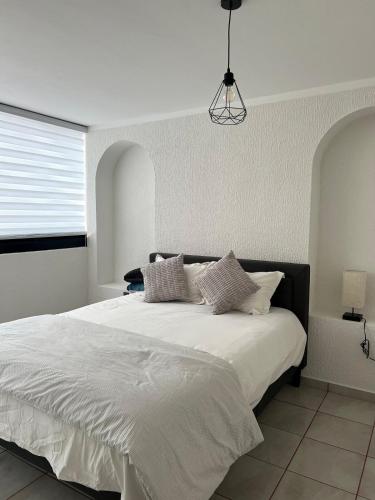 a white bedroom with a large white bed with pillows at 3 - Departamento amplio y centrico in Morelia