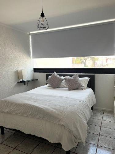 a bedroom with a large white bed with a window at 3 - Departamento amplio y centrico in Morelia