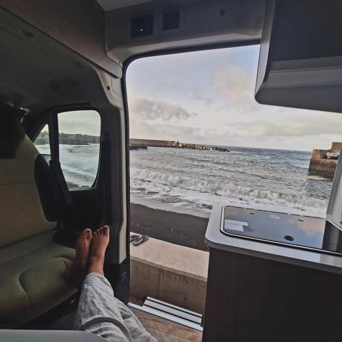a person sitting in a van looking out at the ocean at Camper La Palma, 600 eur de fianza in Santa Cruz de la Palma