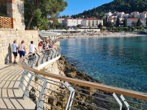a group of people walking along a path next to a body of water at Apartments Villa Alba in Dubrovnik