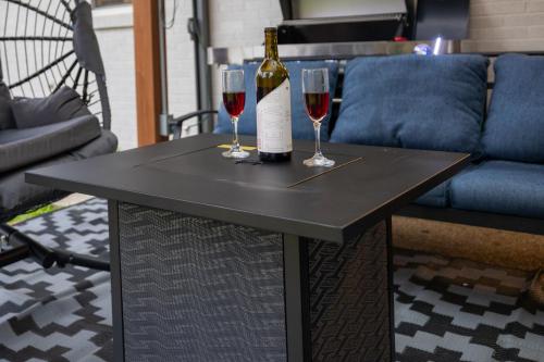 a bottle of wine and two glasses on a table at Pristine & Homely Getaway with 6pple hot tub in Richardson
