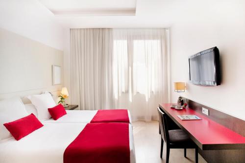 a hotel room with a bed and a desk and a tv at Grupotel Gran Via 678 in Barcelona