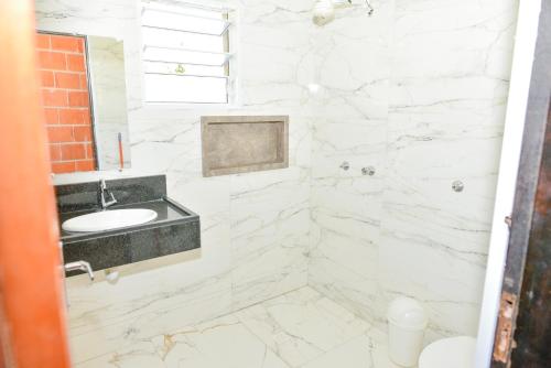 a white marble bathroom with a sink and a mirror at CHACARA HORTOLAN in Mairinque