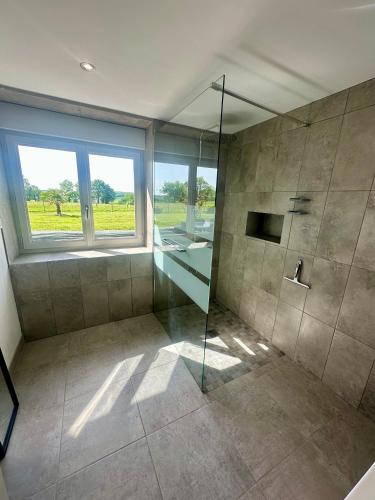 La salle de bains est pourvue d'une douche en verre et d'une fenêtre. dans l'établissement Gîte près du Mont Saint Michel 8 à 10 pers, à Saint-Senier-de-Beuvron