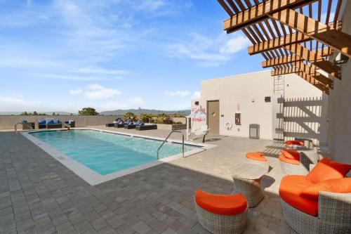 a pool on the roof of a building with orange chairs at Luxurious 2BR Apartment in heart of Silicon Valley in Santa Clara